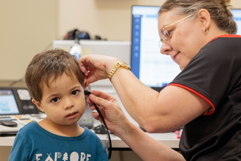 An audiologist performing a hearing health check on an Indigenous child in the clinic.