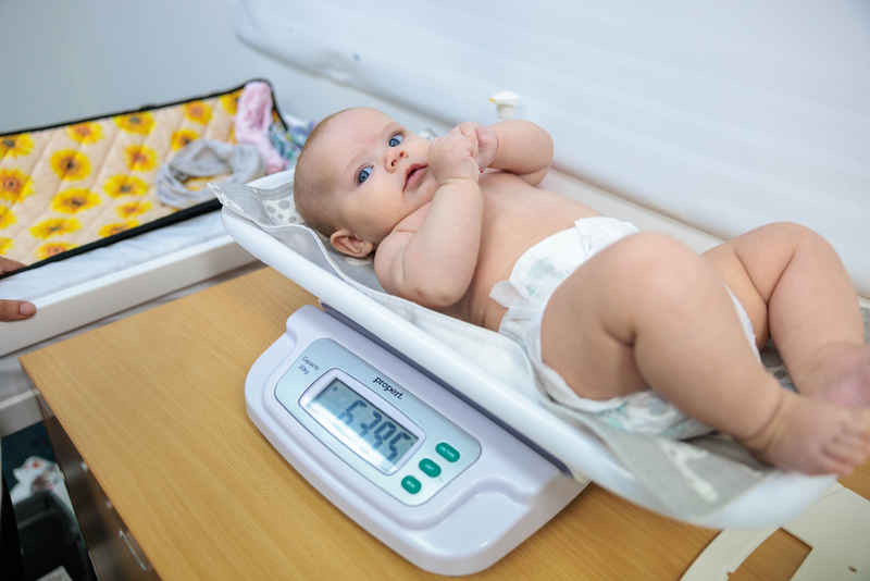 An Indigenous baby at health check, being weighed in a baby scale.