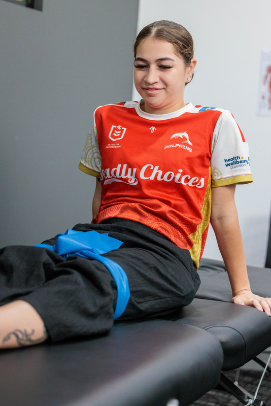 An Indigenous client at physiotherapy session, sitting on an examination table.