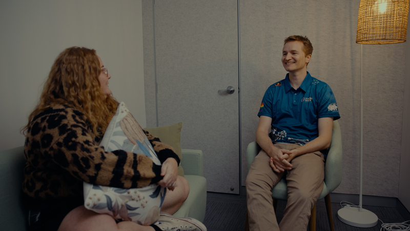 A Pamela Mam Health Centre staff member wearing a blue Staying Deadly team member shirt, sitting in a quiet room yarning with a client.