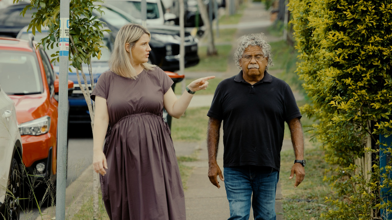 A Pamela Mam Health Centre staff member walking with Uncle Billy, an Indigenous Elder, down a local street.