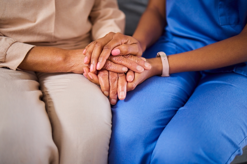Two people - patient and staff member - holding hands in a comforting way.