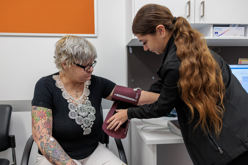 A staff member taking a clients blood pressure yarning about cardiology.